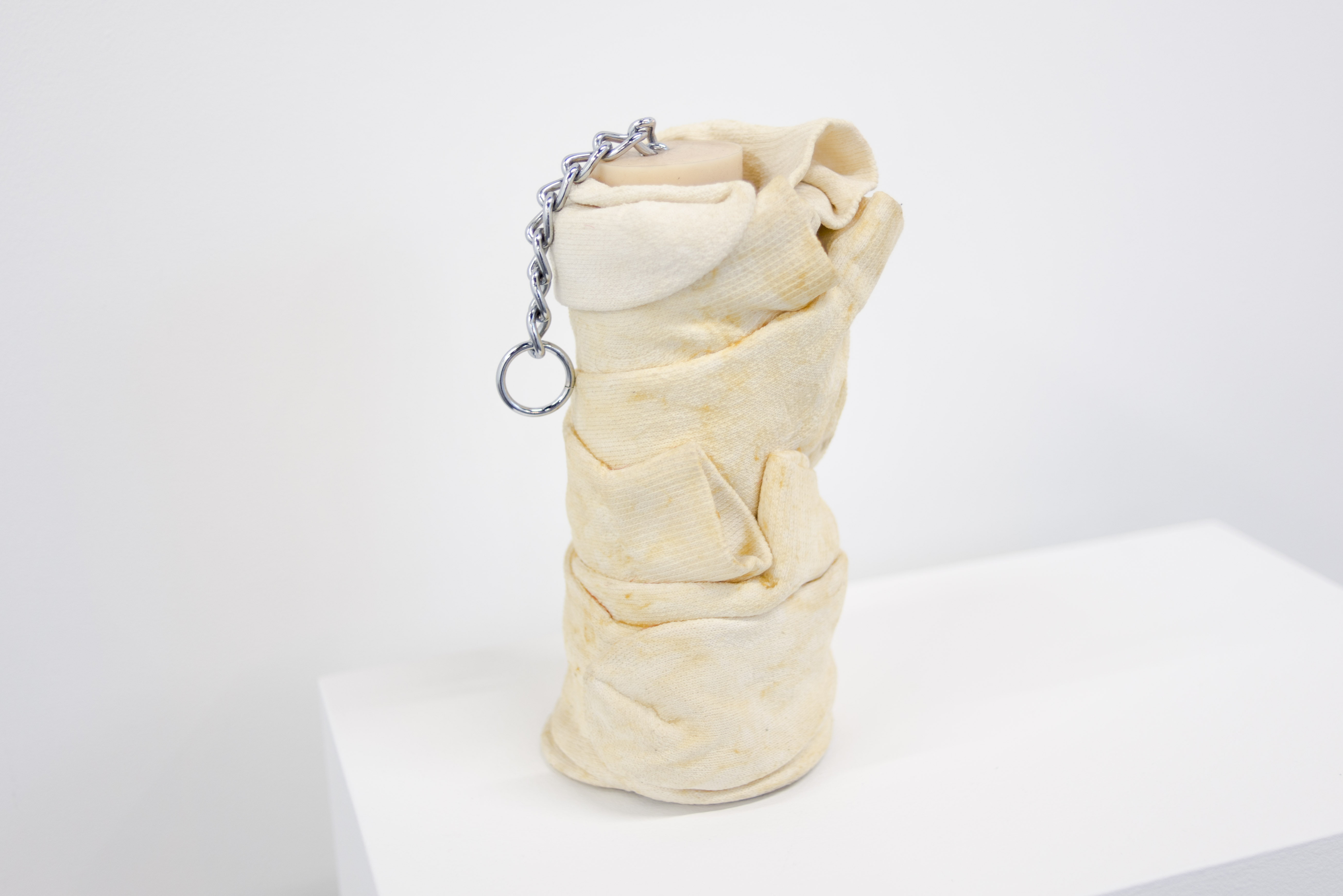 Isaac Pool, 40 Volume, White, a vase covered in soiled white socks with the chain of a dong hanging from its mouth